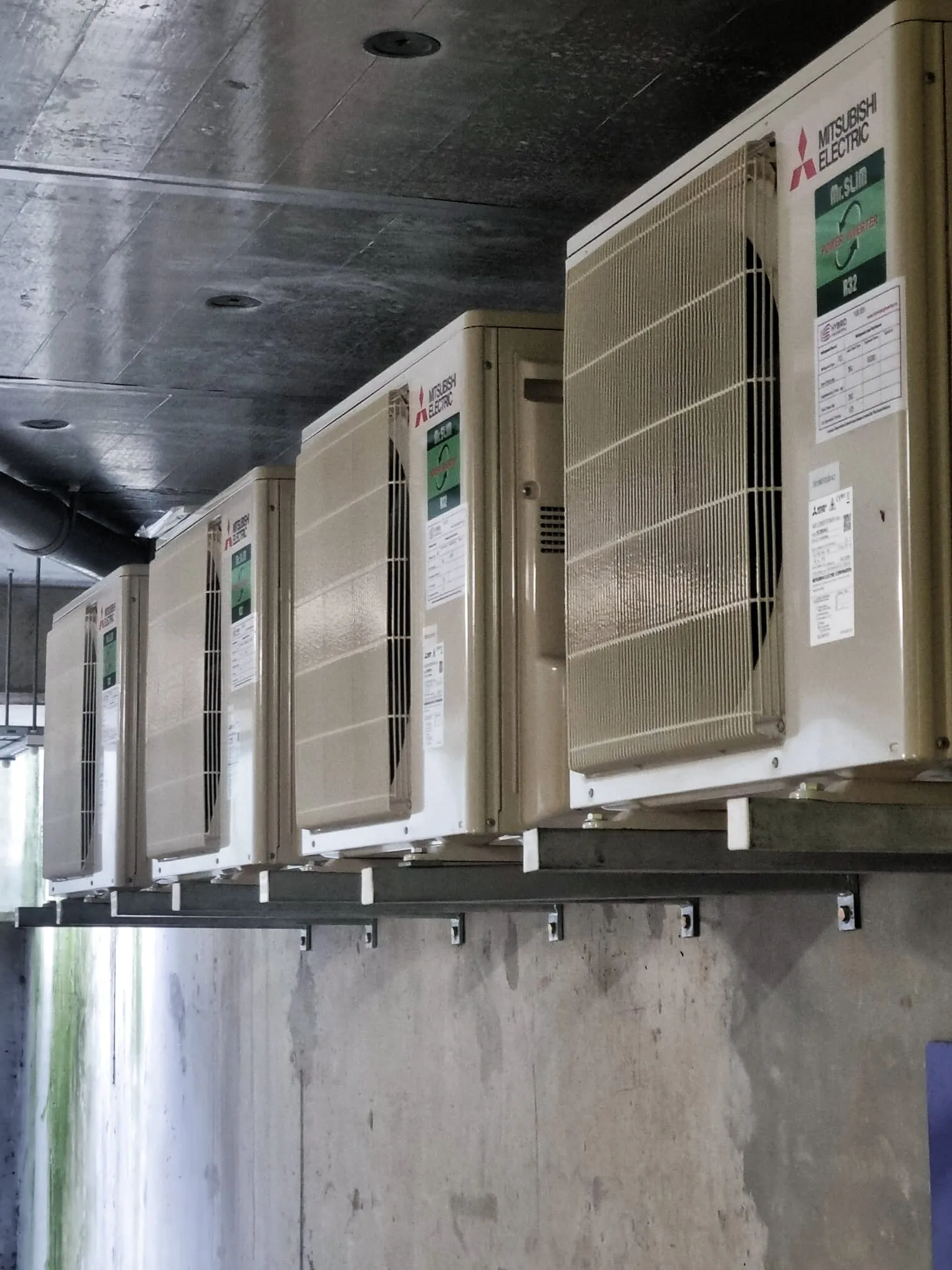 Row of Mitsubishi outdoor units on wall brackets