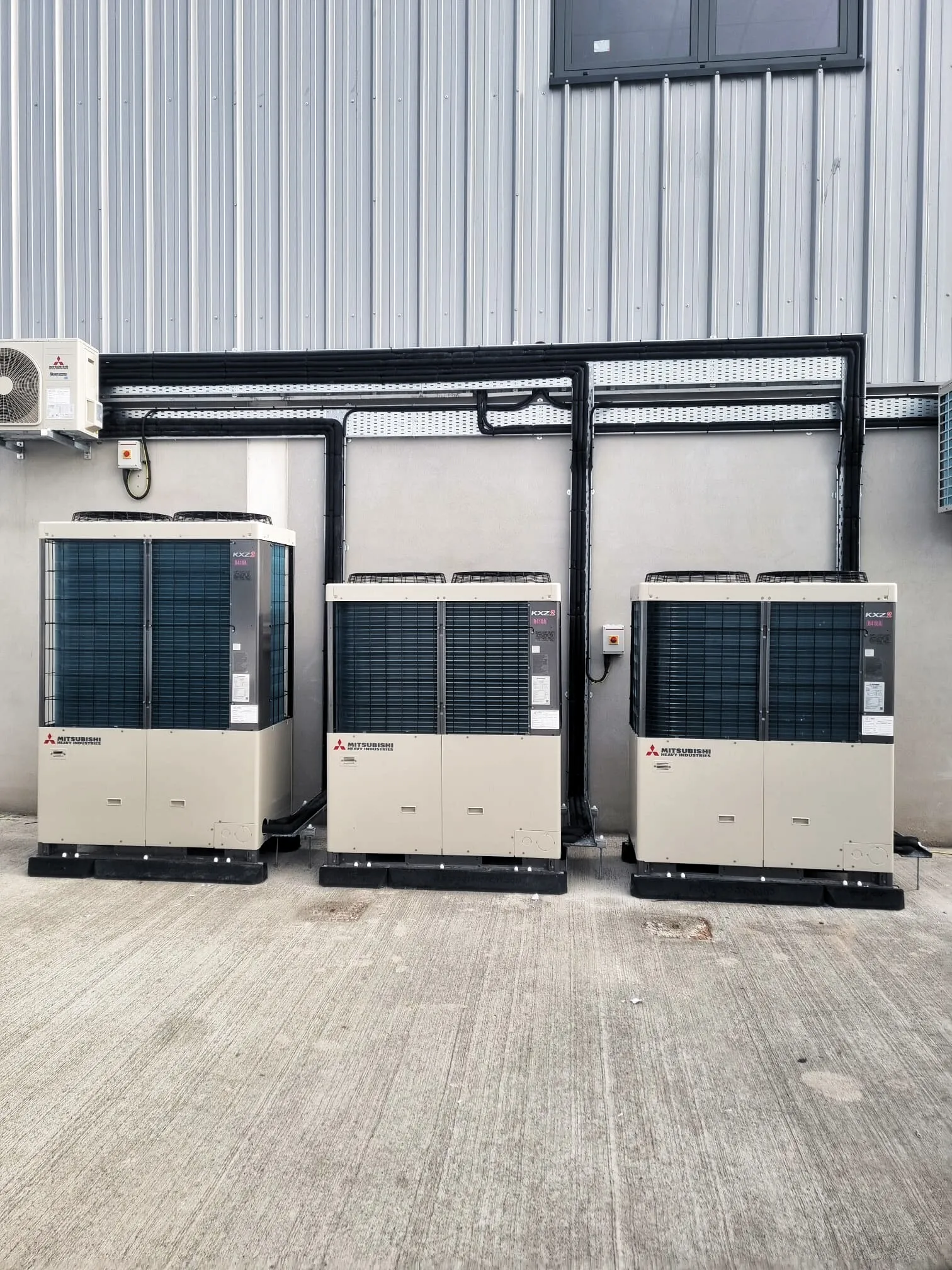 Three Mitsubishi VRF outdoor units installed outside an industrial building